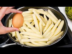 a person holding an egg over some fries in a frying pan on the stove