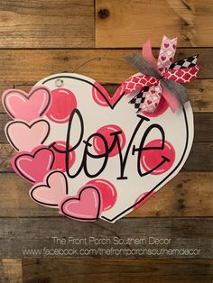 a heart shaped door hanger with the word love painted on it and pink hearts