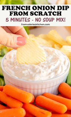 a hand dipping a potato chip into a bowl of ranch dip with carrots and celery