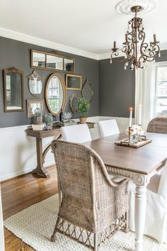 a dining room table with white chairs and a chandelier hanging from the ceiling