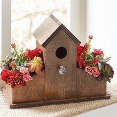 a birdhouse with flowers and succulents in it