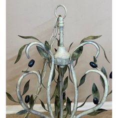 an artistic lamp made out of branches with olives hanging from it's sides