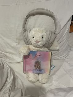 a white teddy bear with headphones and a book