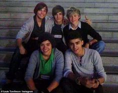 a group of young men sitting next to each other in front of a building with their thumbs up