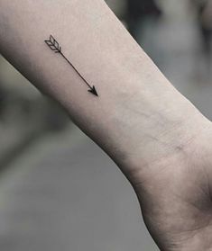 a small arrow tattoo on the left inner arm, with an arrow in the middle