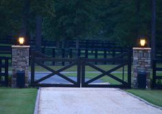 a gate with two lights at the top and an entrance way leading to a driveway