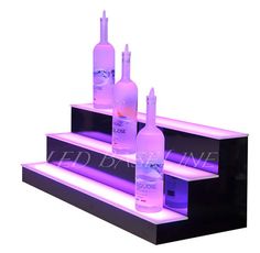 three bottles of alcohol sitting on top of some steps with purple lights in the bottom