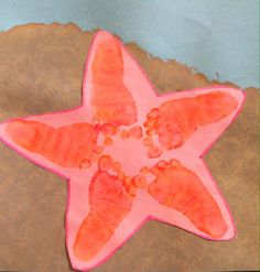 a starfish made out of pink paper on top of a piece of brown paper