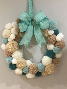 a wreath with pom - poms hanging on the wall next to a blue ribbon