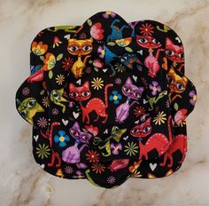 three black and multicolored animal print pot holders on a marble countertop with flowers