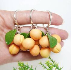 a person holding some fruit on their finger and wearing it as a keychain