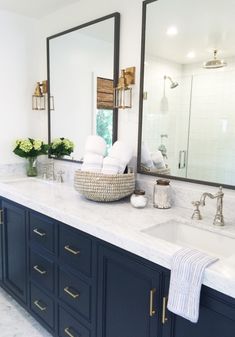 a bathroom with two sinks and mirrors on the wall, along with blue cabinetry