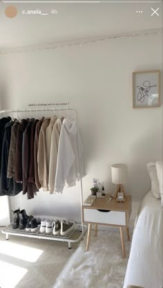 a bedroom with white walls and clothes hanging on the rack