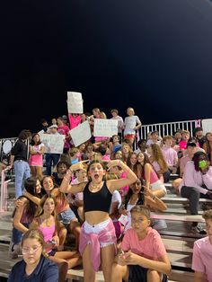 a group of young women sitting on top of bleachers holding signs and standing next to each other