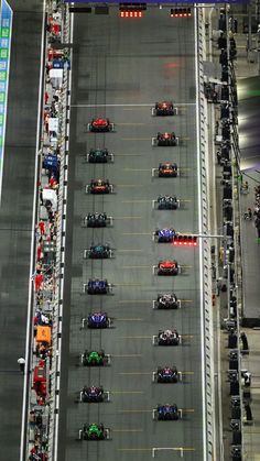 an overhead view of a race track with cars on the road and people standing around