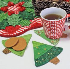 a cup of tea next to some christmas tree coasters