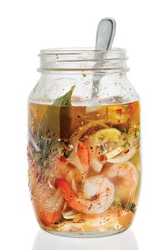 a glass jar filled with food on top of a white table next to a spoon