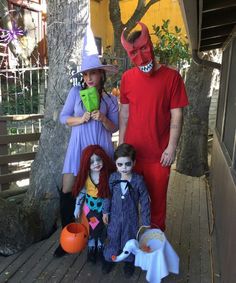 three people in costumes standing next to each other on a wooden deck with pumpkins