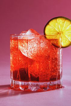 an orange slice is sitting on top of a glass with ice and lemon wedges