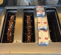 three donuts sitting on top of a toaster oven with wrappers wrapped around them