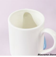 a white coffee cup with a spoon sticking out of it's side on a purple background