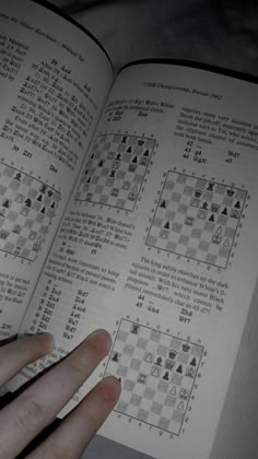 a hand is holding an open book with chess pieces on the pages and numbers in it