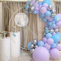 a balloon arch is decorated with blue, lavender and silver balloons