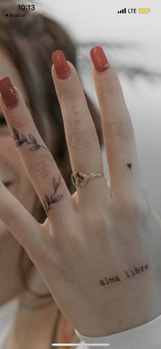 a woman's hand with two small tattoos on it and the words i love you written on her fingers