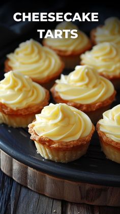 small cupcakes with white frosting sitting on a black plate next to the words cheesecake tarts