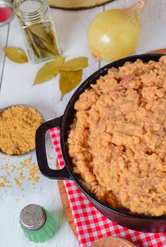 a pot filled with macaroni and cheese on top of a red checkered cloth