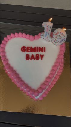 a cake shaped like a heart with candles in the shape of a baby's name