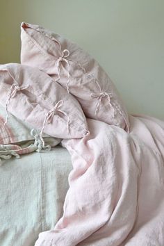 an unmade bed with pink sheets and pillows