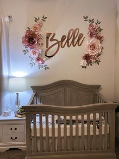 a baby's room with a crib, dresser and flower wall hanging on the wall