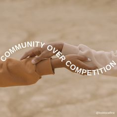 two hands holding each other with the words community over competition written in white on them