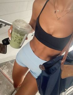 a woman in blue shorts holding a drink