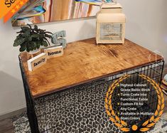 a wooden table topped with a bird cage next to a plant and a painting on the wall