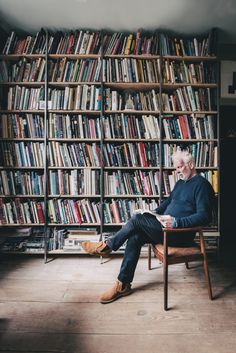 an older man sitting in a chair in front of a book shelf filled with books