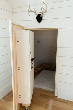 an open cabinet in the corner of a room with a deer head mounted on the wall