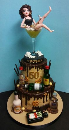 a cake with a woman sitting on top of it and liquor bottles around the base