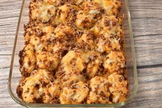 a casserole dish with cheese and meat in it sitting on a wooden table