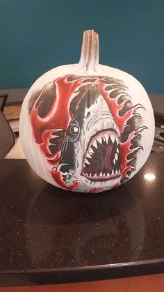 a painted pumpkin with a shark on it's face and flames coming out of its mouth