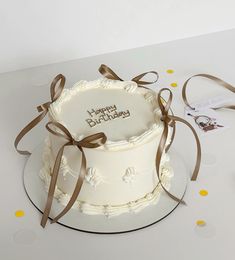 a white cake with brown ribbon and happy birthday written on it