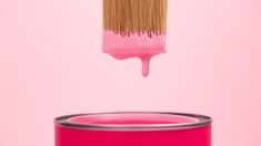 a pink paint can being dipped by a brush