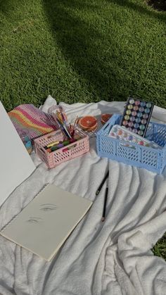 an open notebook on a blanket next to some art supplies