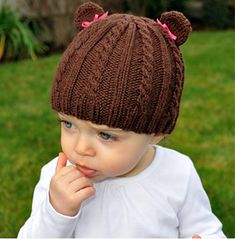 a baby wearing a brown knitted bear hat