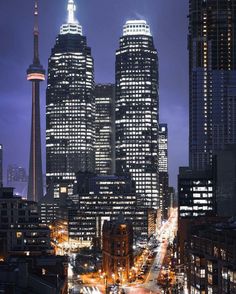 the city skyline is lit up at night, with skyscrapers in the foreground