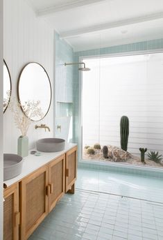 a bathroom with two sinks and mirrors on the wall next to each other in front of a cactus