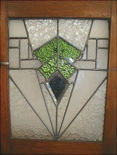 a stained glass window with green plants in the center and bottom panel, on a wooden frame