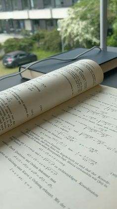 an open book sitting on top of a table next to a window with cars in the background