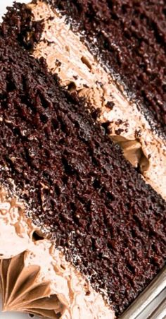 a slice of chocolate cake with white and brown frosting on a plate next to a fork